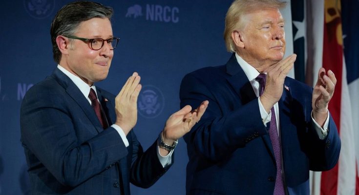 Two men in dark suits clapping on a stage with NRCC logo and American flag in background