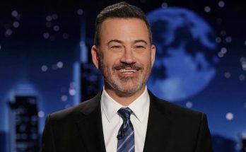 smiling host in suit with moonlit backdrop on talk show set