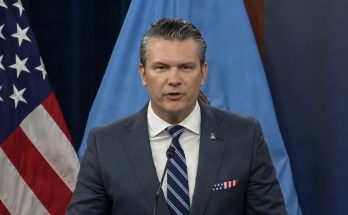 secretary of Defense Pete Hegseth speaking at Pentagon podium with American flag and blue