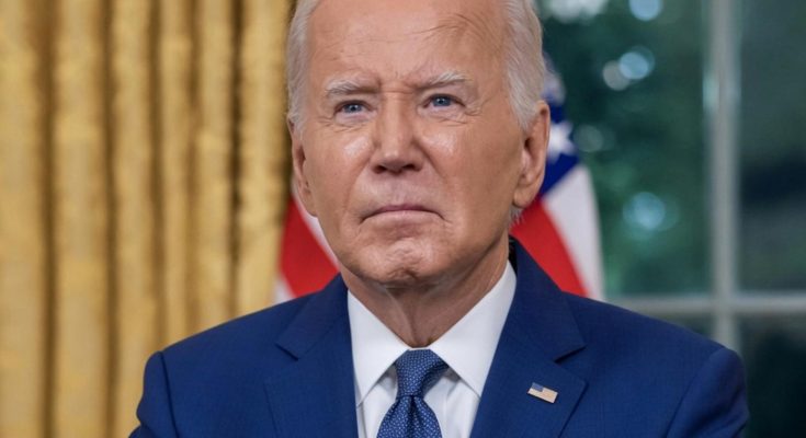 president Joe Biden in blue suit and tie seated at desk with gold curtains and American
