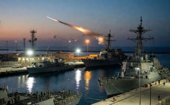warships docked at naval base with missile launch at dusk