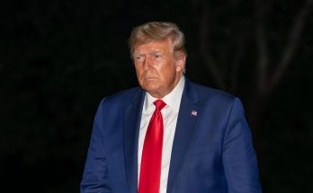 person in blue suit with red tie outdoors at night