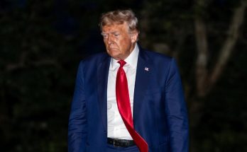 man in blue suit with red tie walking outdoors at night