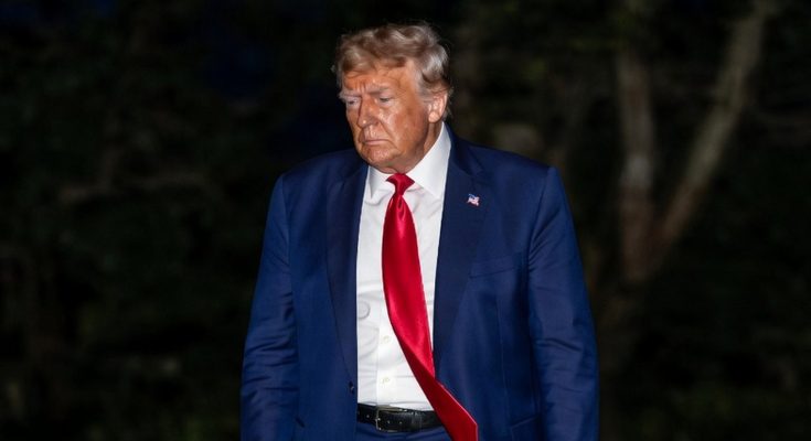 man in blue suit with red tie walking outdoors at night