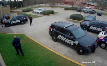 police vehicles surround a municipal building parking lot as officers converge near a