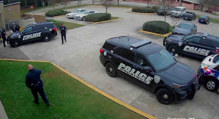 police vehicles surround a municipal building parking lot as officers converge near a