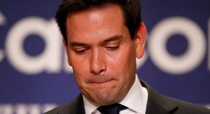 man in suit looking down, appearing contemplative at a conference