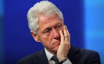 thoughtful man in suit on blue background, hand on face