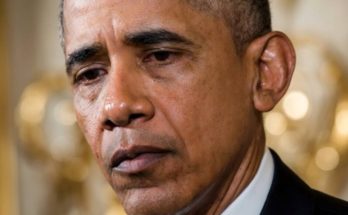 former President Barack Obama speaking at podium with solemn expression during formal