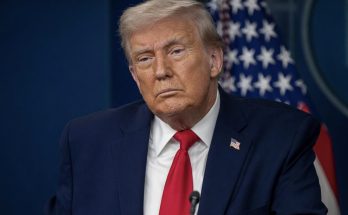 donald Trump at podium with stern expression, American flag behind him, headline about