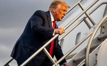 man in suit climbing airplane stairs under cloudy sky, focus on travel
