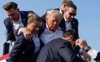 security personnel assist a man descending stairs at outdoor event