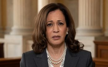 vice President Kamala Harris wearing a double-strand pearl necklace and dark suit speaks