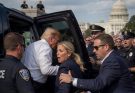 security detail escorts a man into vehicle near Capitol building