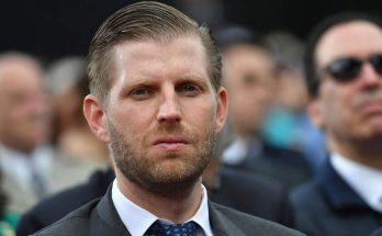 man in suit at outdoor event, focused expression, blurred crowd