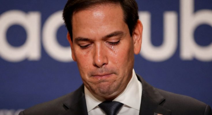marco Rubio with tears streaming down his face at a podium with breaking news banner