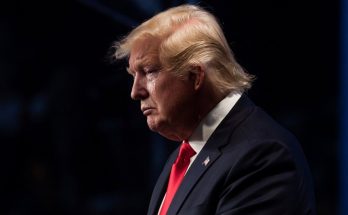 serious man in suit with contemplative expression on stage