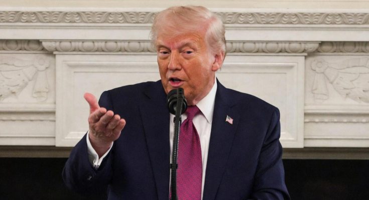 man in suit speaking at microphone in formal setting