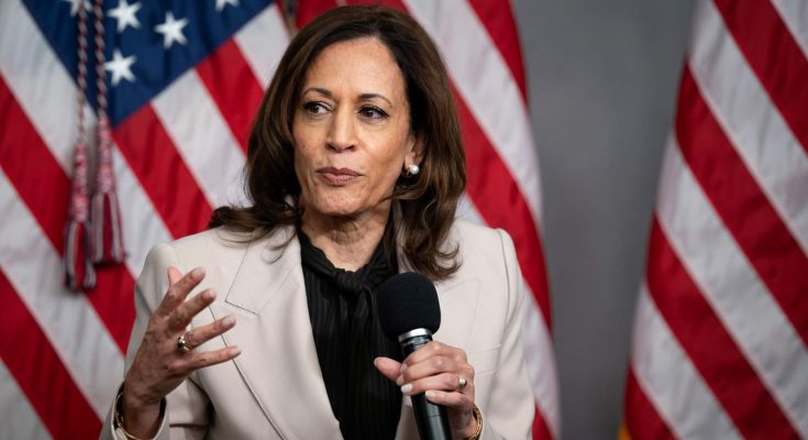 woman in suit speaking with American flags in background