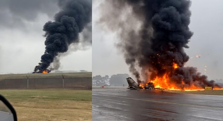 aircraft wreckage engulfed in flames on wet runway with massive black smoke plume rising