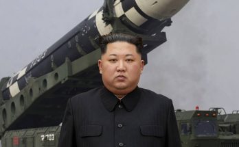 leader standing before military missile on transporter, foggy background