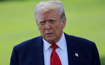 serious man in suit with red tie, outdoors setting