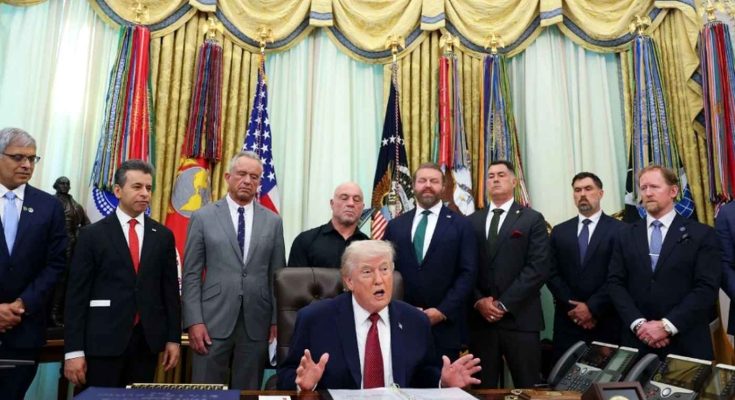 donald Trump seated at Oval Office desk gesturing while speaking, surrounded by officials