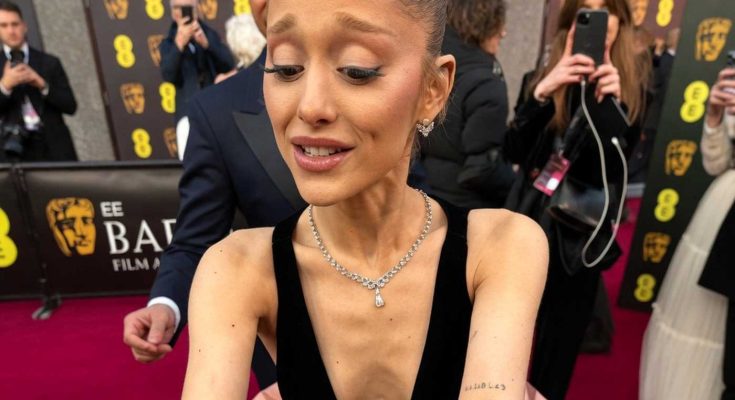 ariana Grande signing autographs at BAFTA red carpet wearing black velvet bodice and pink