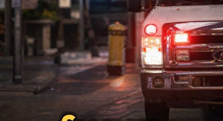 emergency vehicle with flashing red and blue lights on wet city street at night with bold