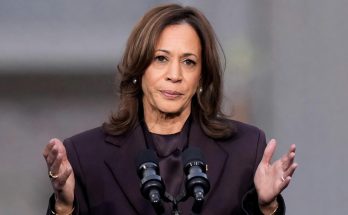 woman speaking passionately at podium during outdoor event