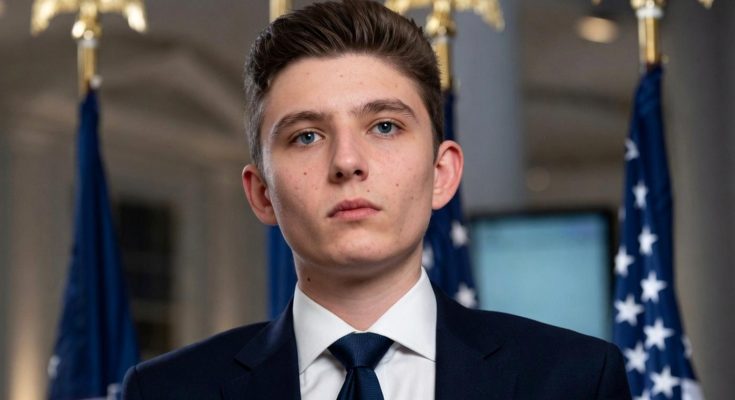young man in suit with flags in background, serious expression
