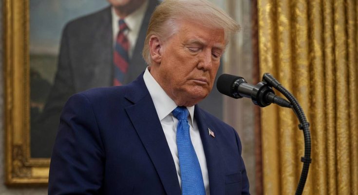 donald Trump reading from notes at a podium with breaking news banner and portrait of
