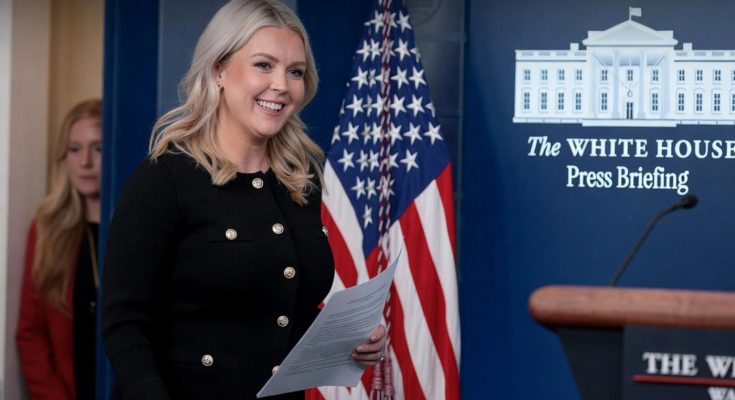 smiling woman holding papers at White House press briefing