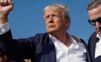 man raising fist confidently among security under clear sky