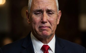 man in a suit with emotional expression, dimly lit setting