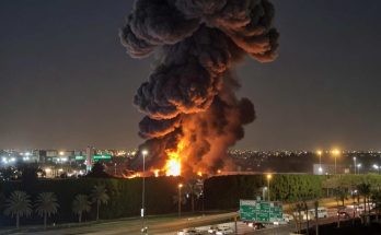 massive fire and smoke near busy freeway at night
