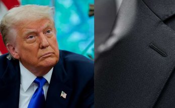 leader in blue suit with American flag pin, serious expression