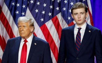 donald Trump and son Barron Trump stand side by side in navy suits before American flags