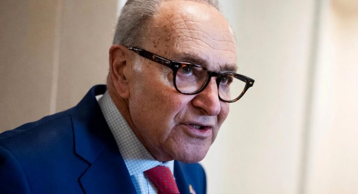 man in blue suit speaking passionately indoors, wearing glasses