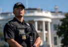 secret Service agent stands alert outside White House during security lockdown with press
