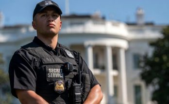 secret Service agent stands alert outside White House during security lockdown with press